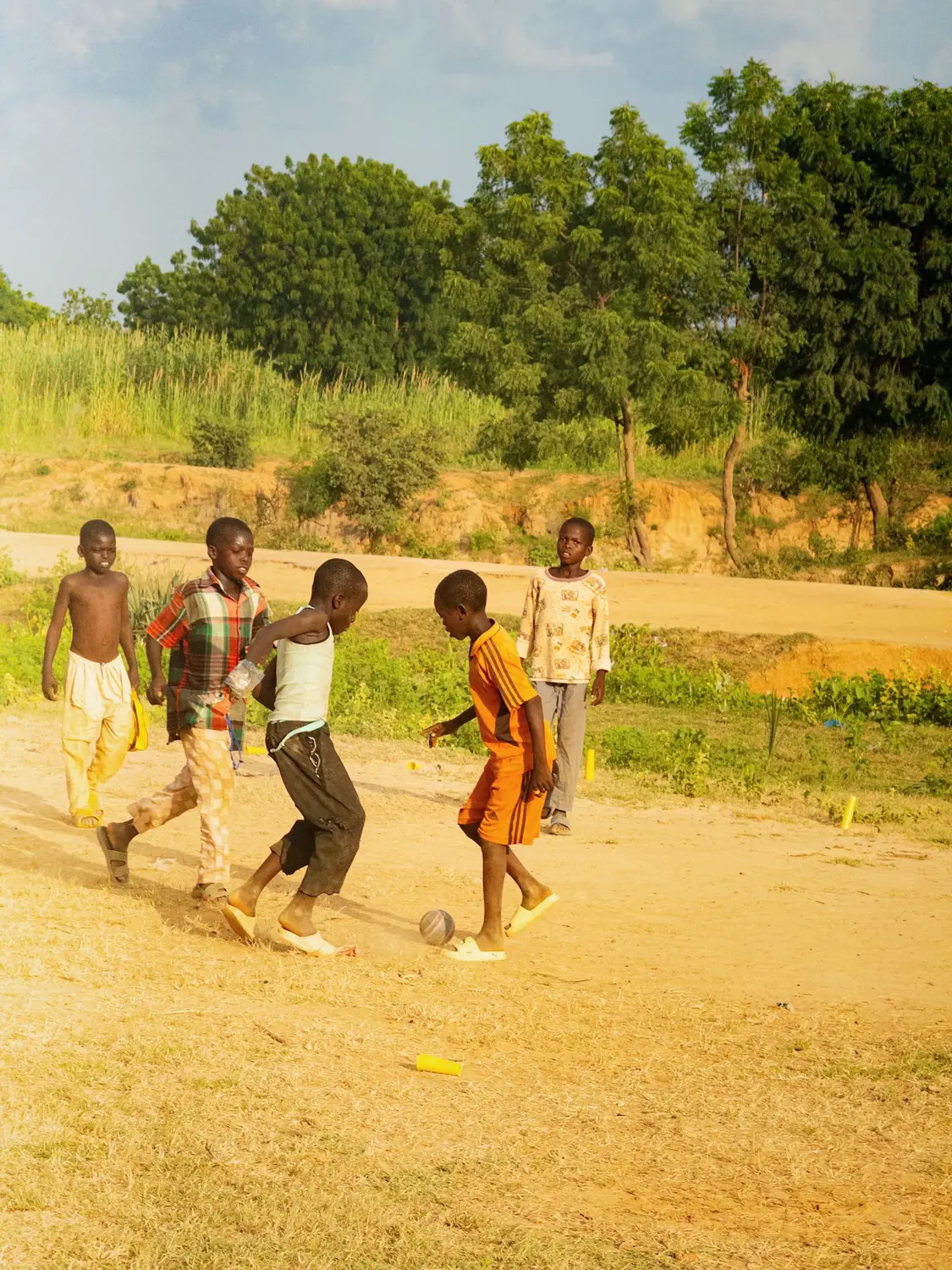 Children playing football on a dusty field